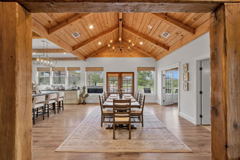 Elegant dining room with exposed wood beam ceiling, hardwood floors, and large windows offering natural light.