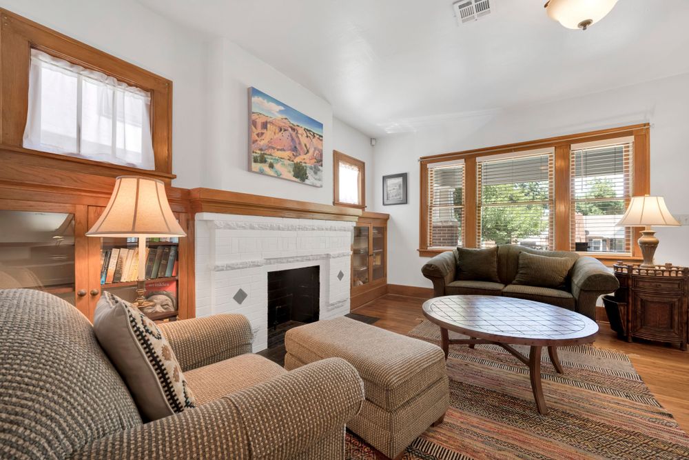 Cozy living room with white fireplace, wood trim, brown sofas, and circular coffee table in natural light.