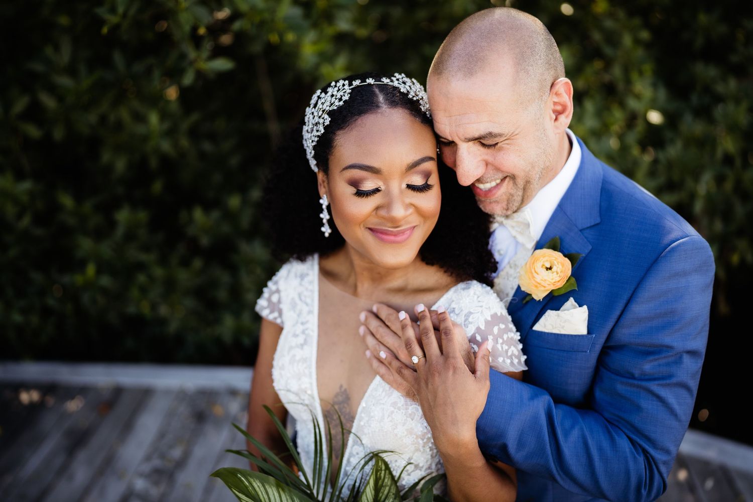 A romantic wedding couple embraces outdoors in a garden setting during their special day.