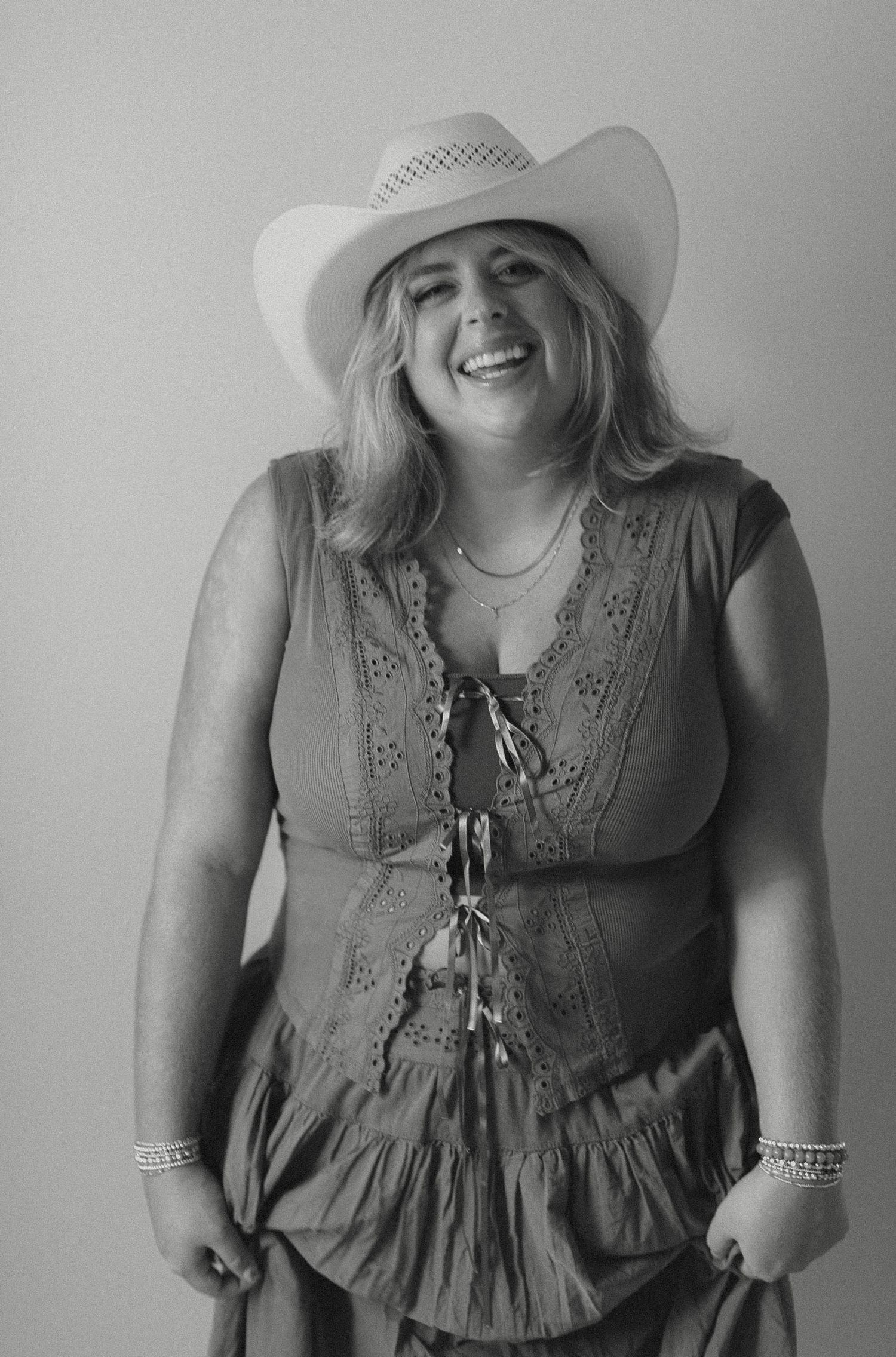 Portrait of person in denim jacket and brown cowboy hat against dark background.