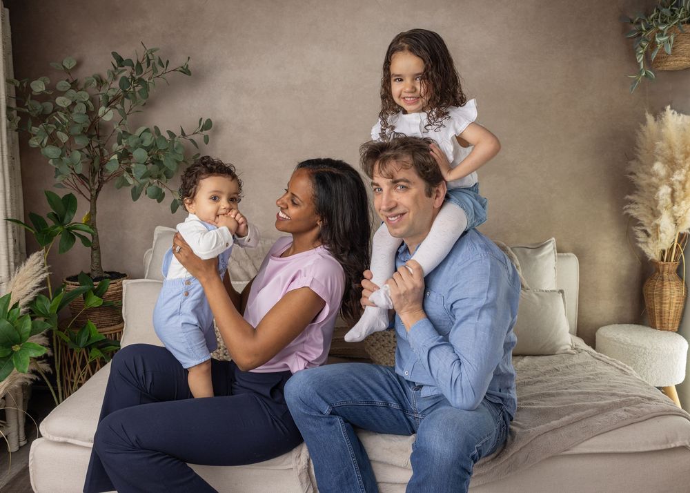 A collage of heartwarming family moments showing parents and children laughing together on a cozy gray couch.