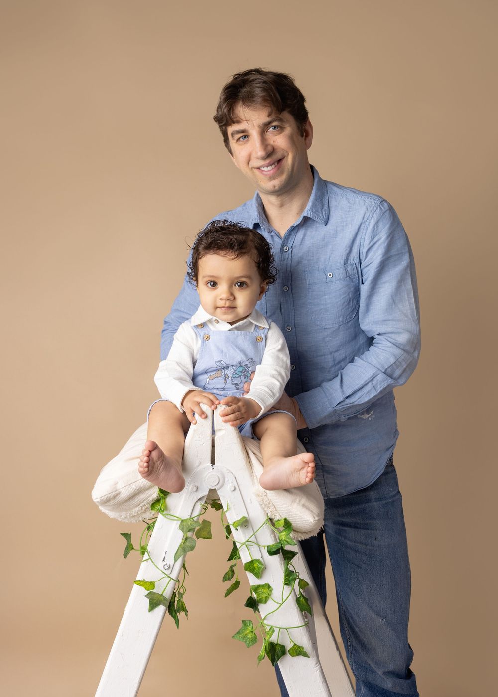 A series of sequential photos showing a person in blue holding a baby by a white lattice with green ivy growth.