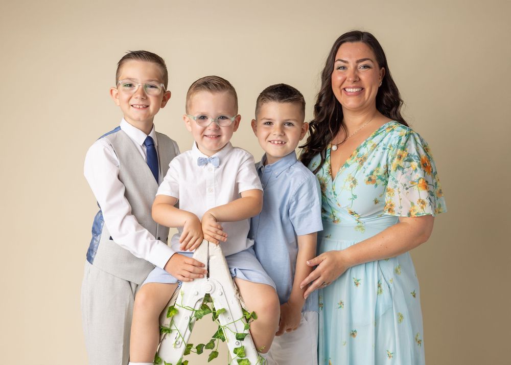 A family wearing coordinated light blue and white outfits poses together against a neutral backdrop for formal portraits.