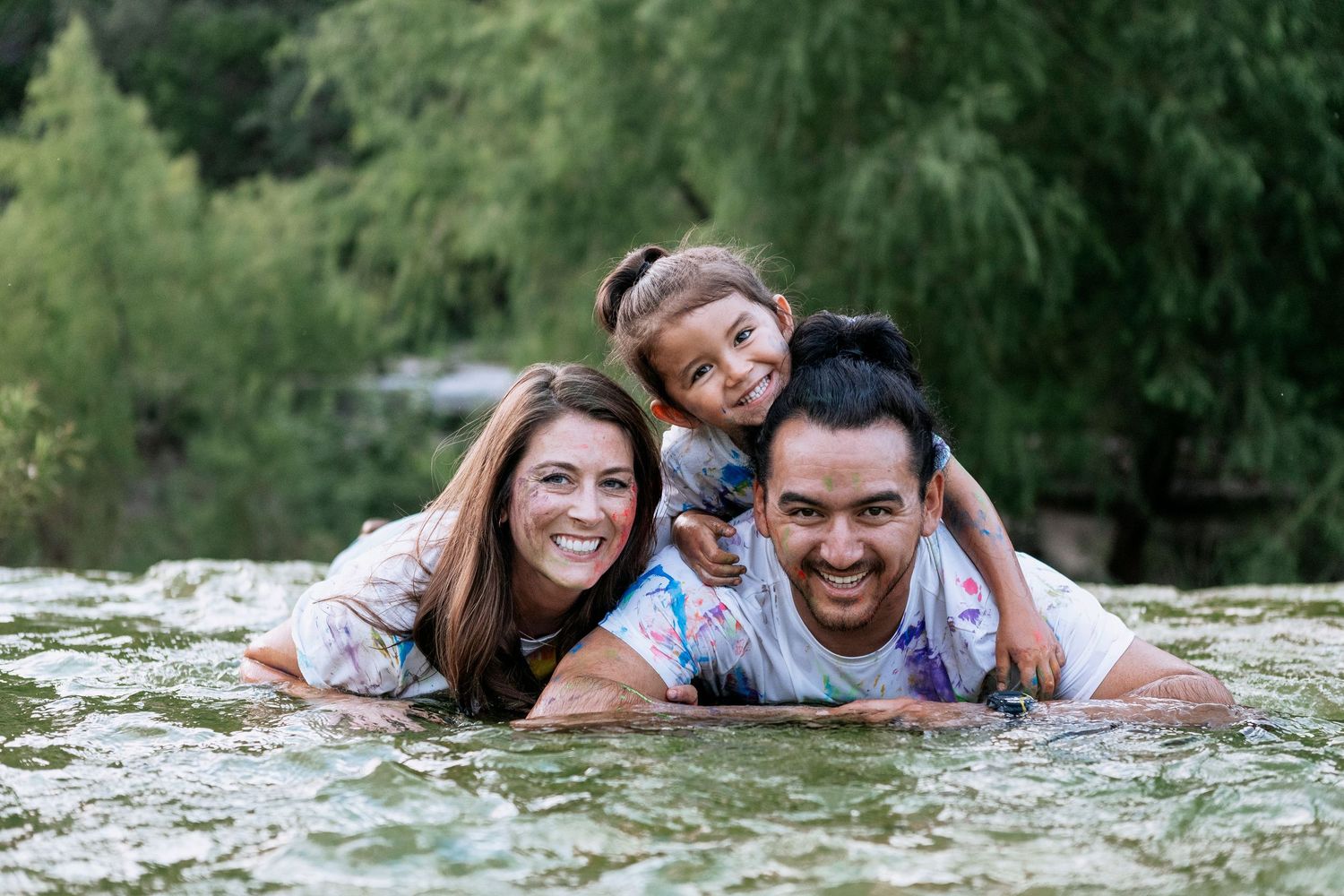 Group of friends having fun together outdoors while lying down and posing for casual photos in nature setting.