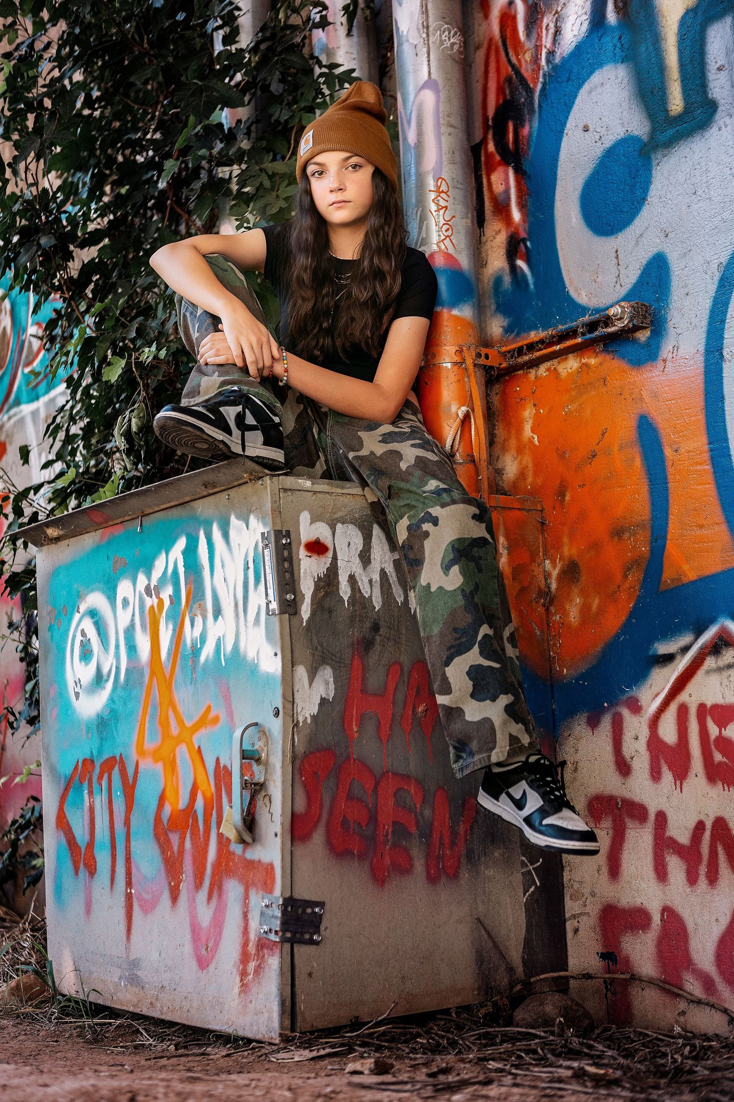 Urban photoshoot series against graffiti wall showing fashion poses in an edgy street setting with orange and blue artwork.