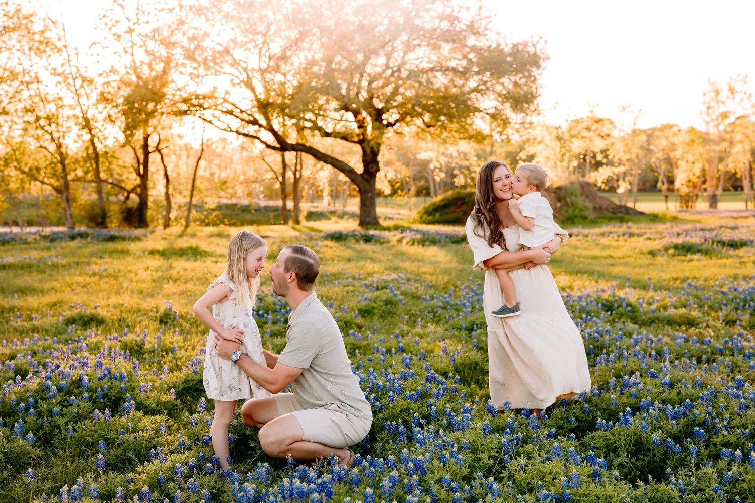 Family of four walking through a bluebonnet field at golden hour during an outdoor family photography session in Spring, Texas