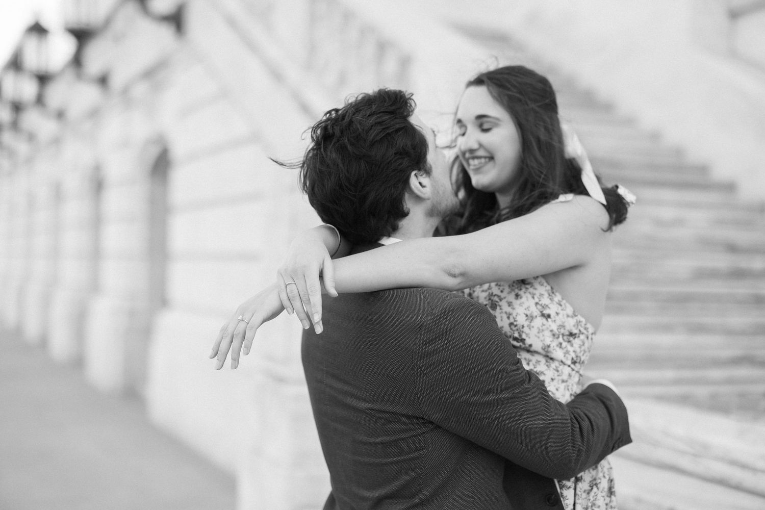 A black and white photograph captures a couple dancing in a sunlit field.