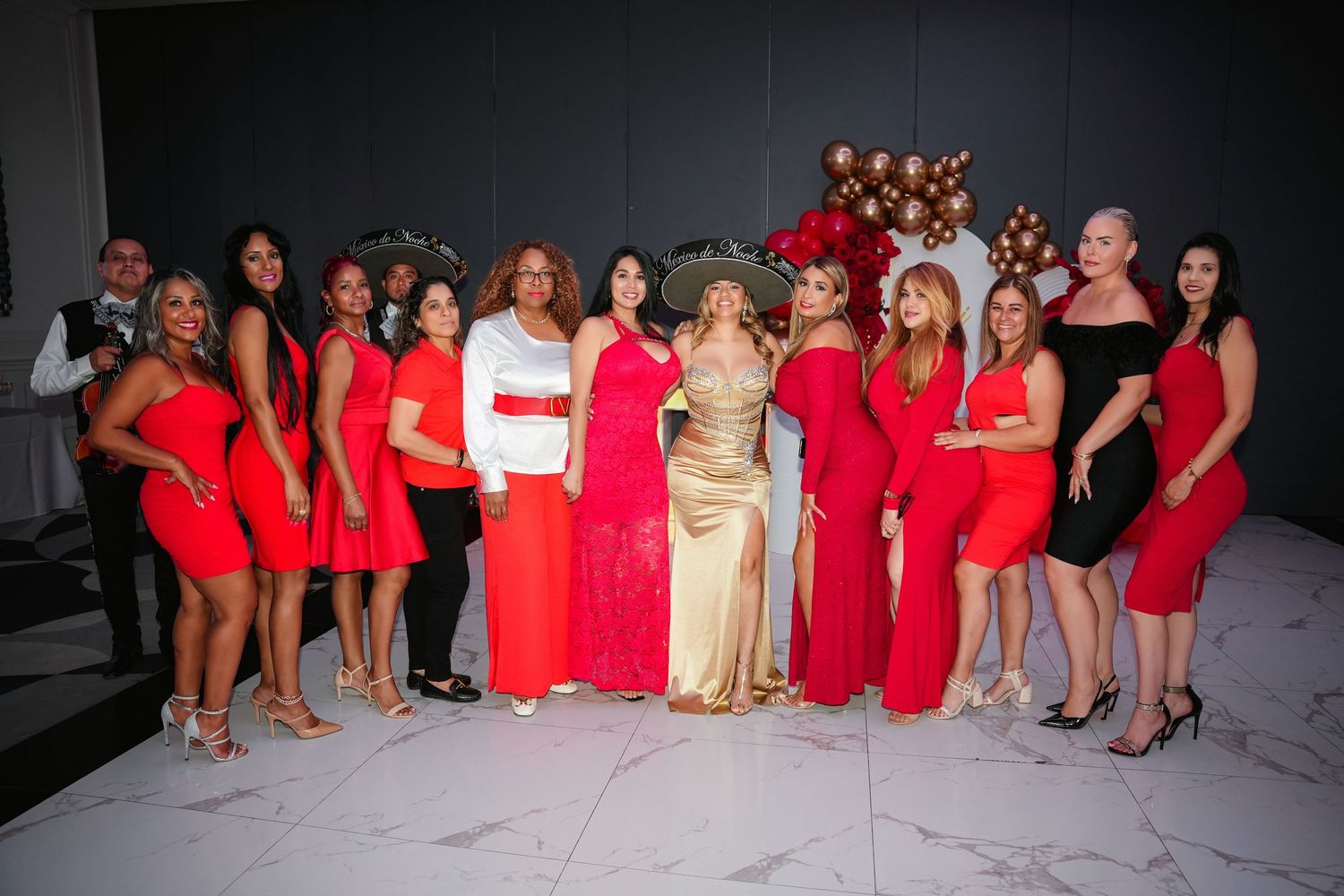 Group of women in red outfits posing together at a festive party with balloon decorations in the background. Toronto GTA