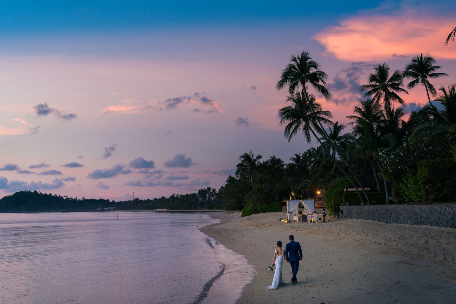 Newlyweds walking on the beach with embracing sunset at InterContinental Koh Samui Resort in Thailand