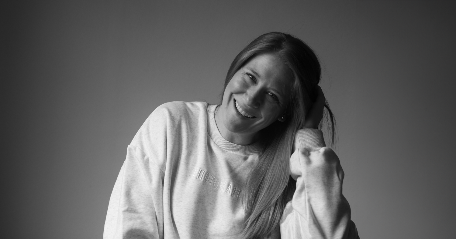 Black and white portrait of someone in a white sweater with a gentle smile.