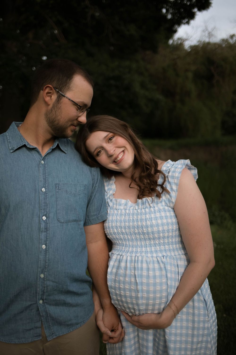 A couple shares a loving embrace while wearing coordinating blue outfits outdoors.