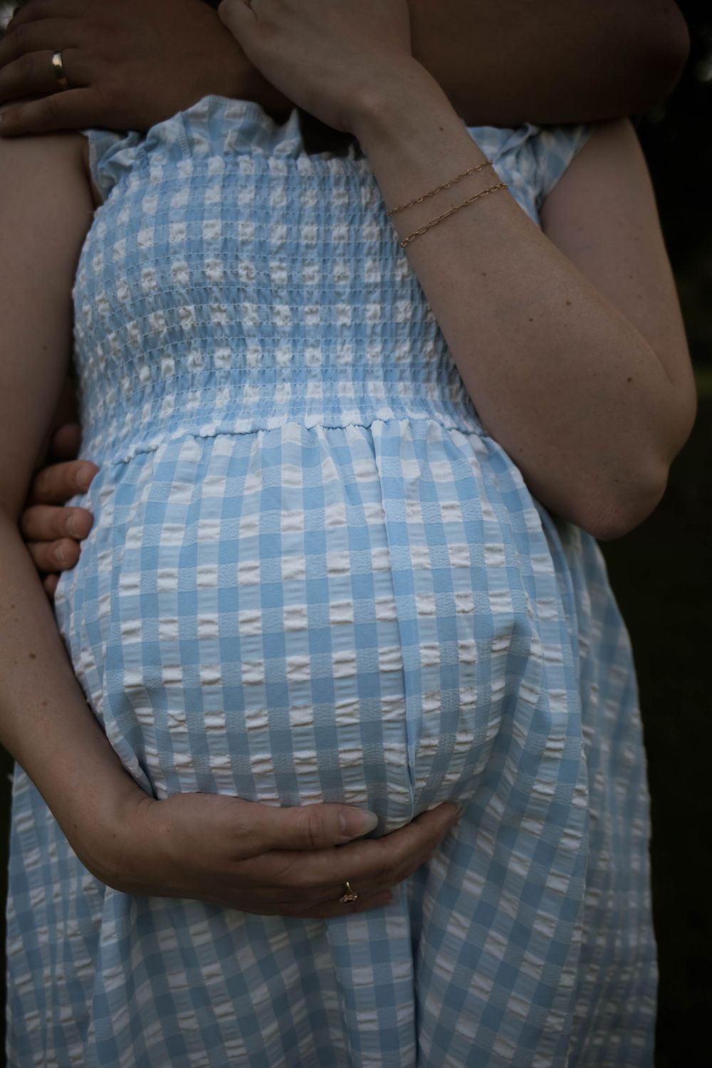 Close-up detail of a blue and white gingham maternity dress.