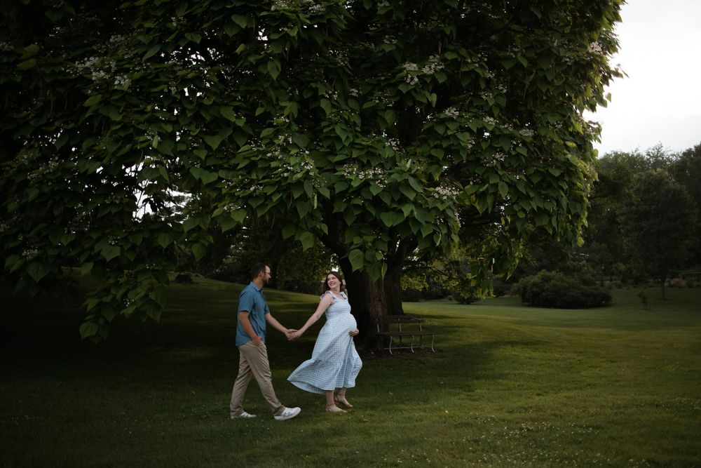 Couple walking together in a green park setting during sunset.