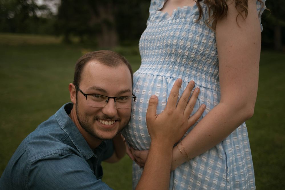 Couple embracing outdoors with person wearing blue gingham dress.