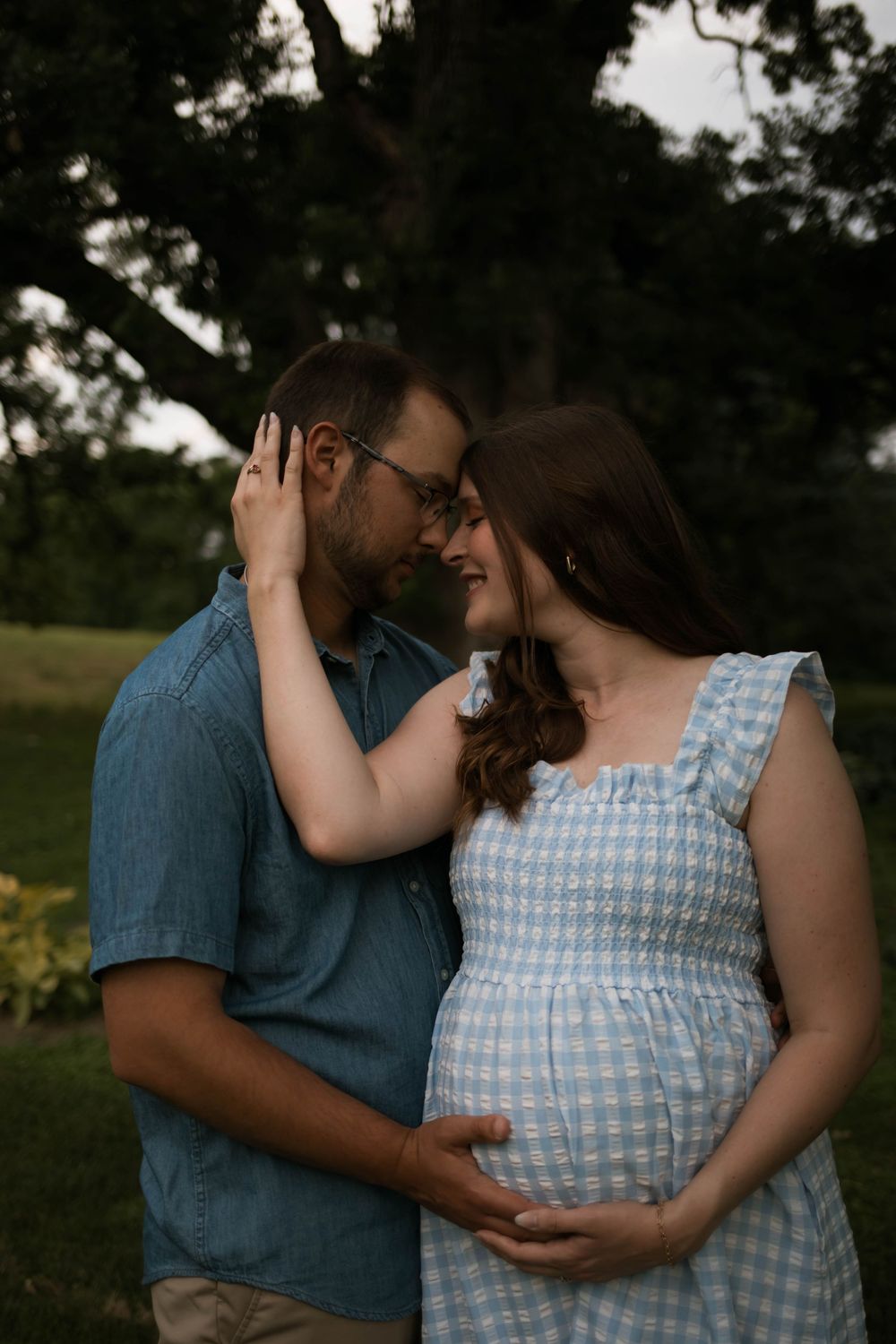 Intimate outdoor maternity photoshoot with couple in casual attire.