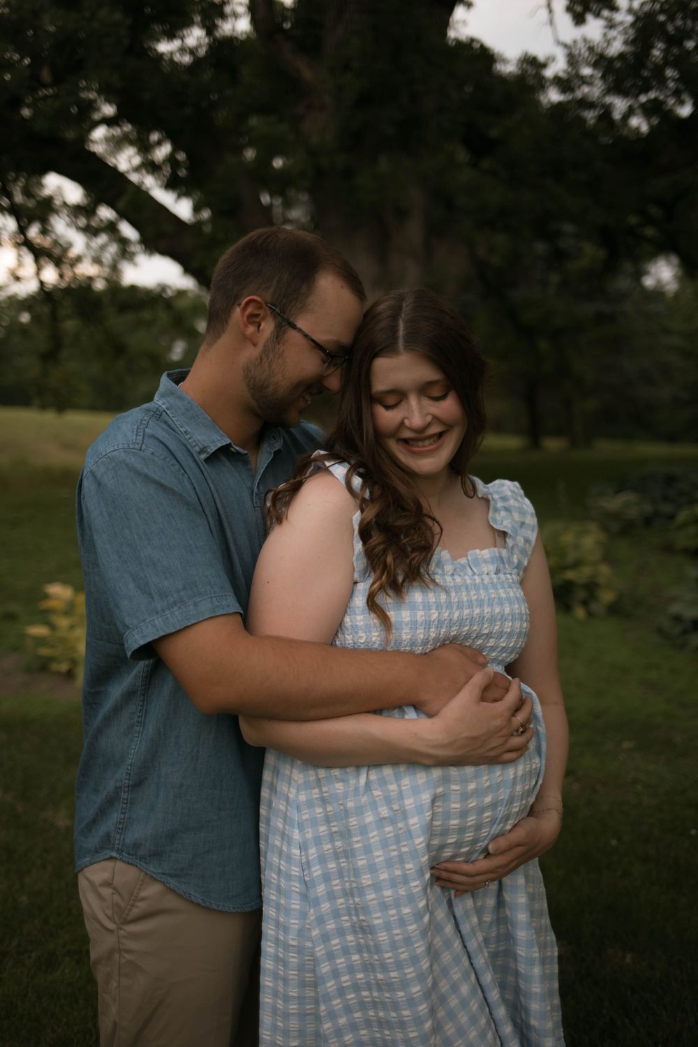Tender moment between couple during outdoor pregnancy photoshoot.