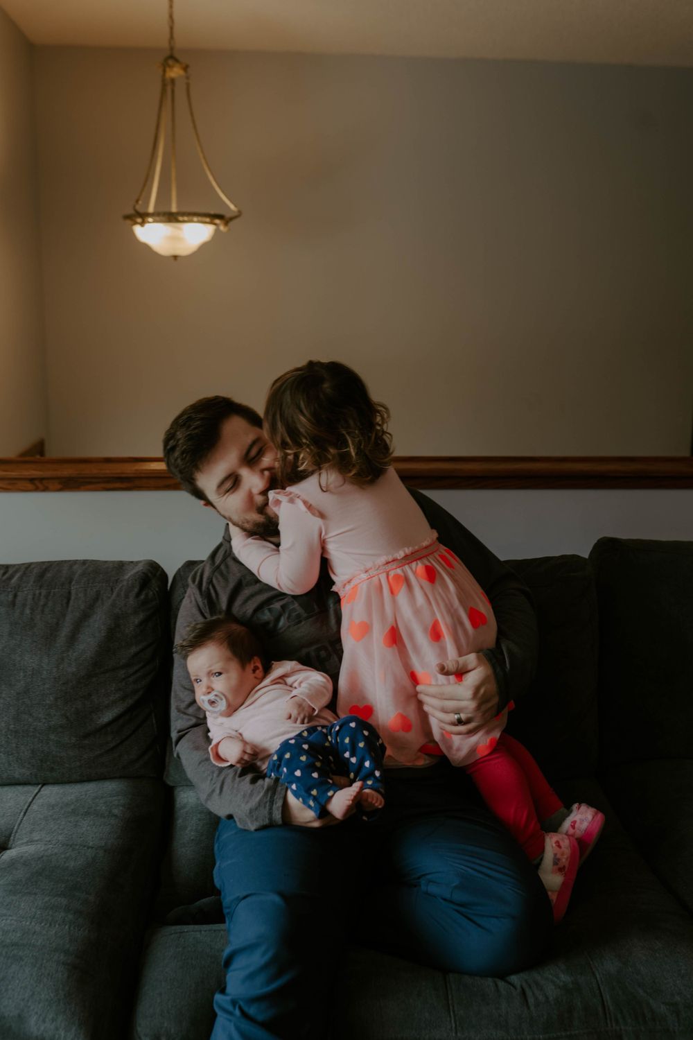 Intimate family moment captured on grey couch in living room.