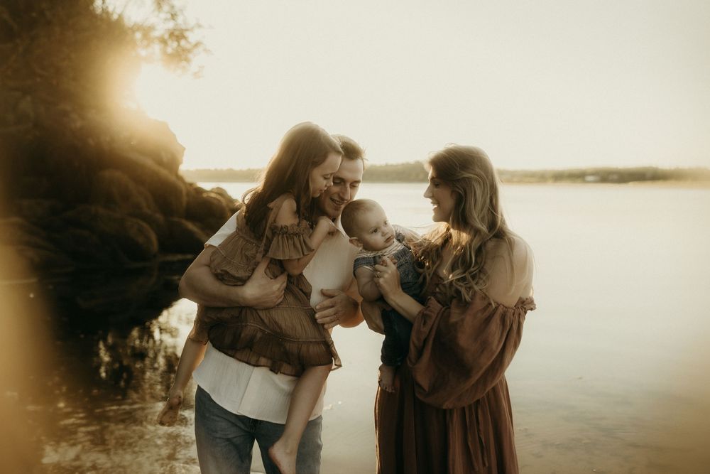 A family shares an intimate moment together by a sunlit lake.