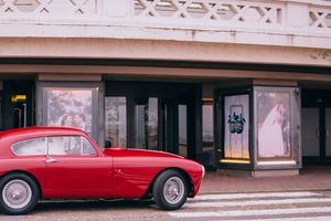 A classic red vintage car parked in front of a historic building with ornate architecture.