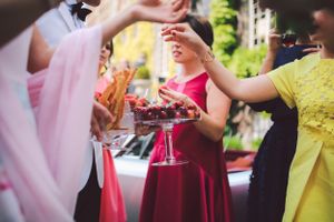 Elegant party guests holding cocktail glasses at outdoor reception.