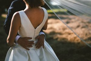Close-up shot of elegant white wedding dress with zipper detail at sunset.