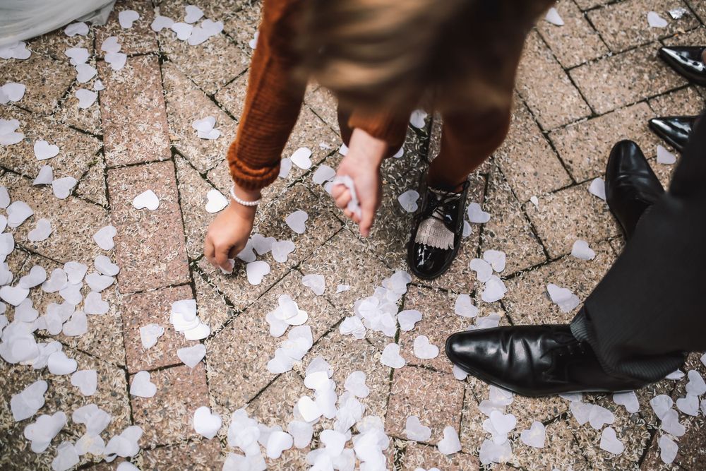 Feet of couple standing on ground covered with white flower petals.