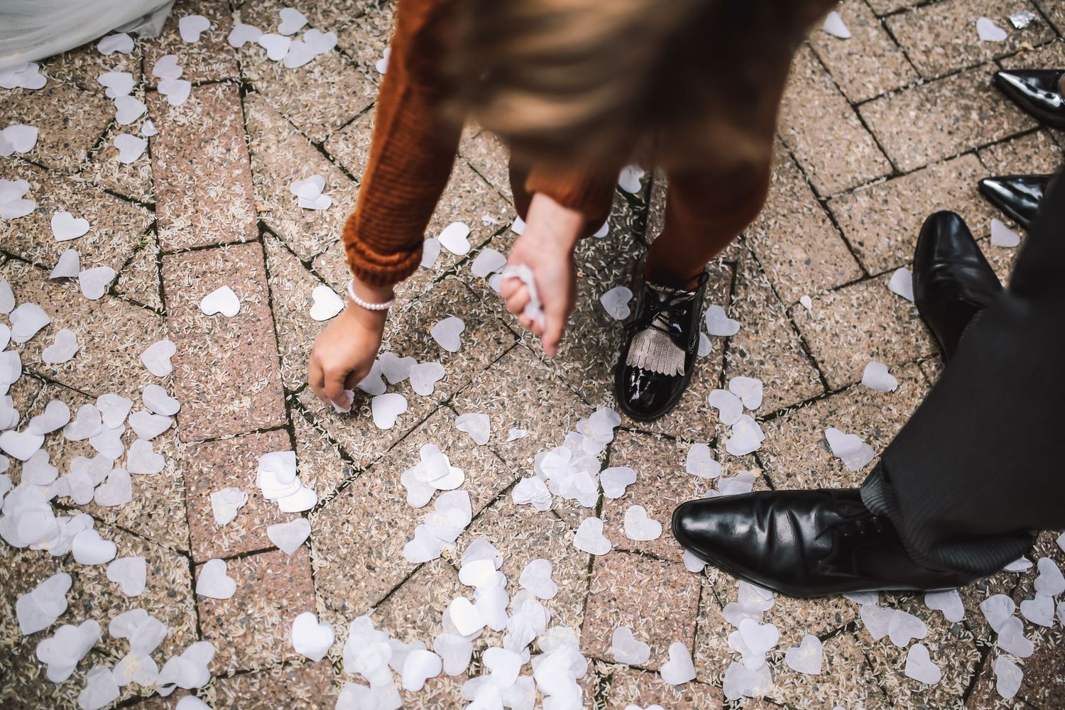 Feet of couple standing on ground covered with white flower petals.