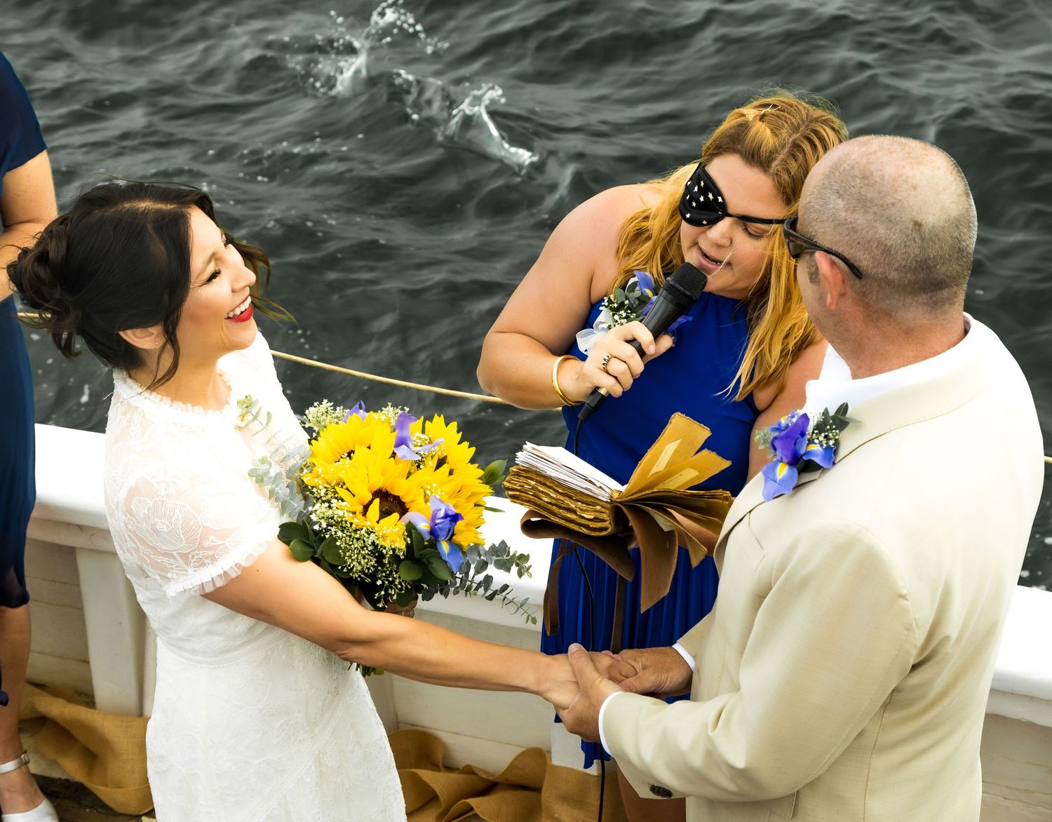 Wedding party members gather on a boat deck with ocean waves visible in the background.Shot By Zeus Holbrook San Diego Wedding Photographer