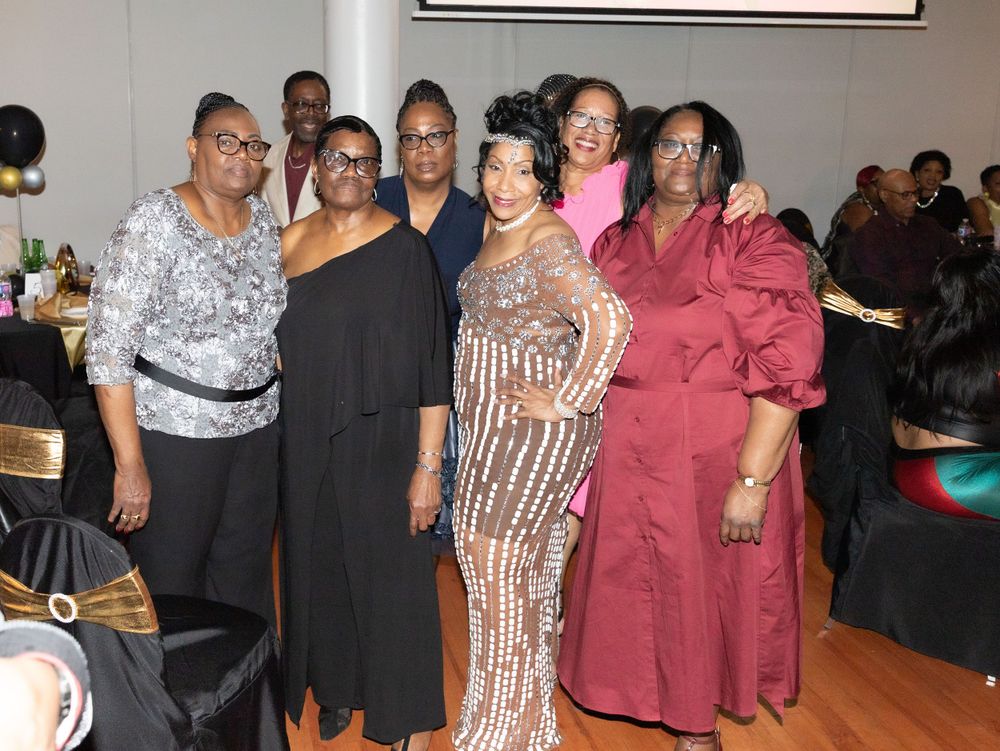 Group celebrating at formal event wearing elegant attire in party venue.