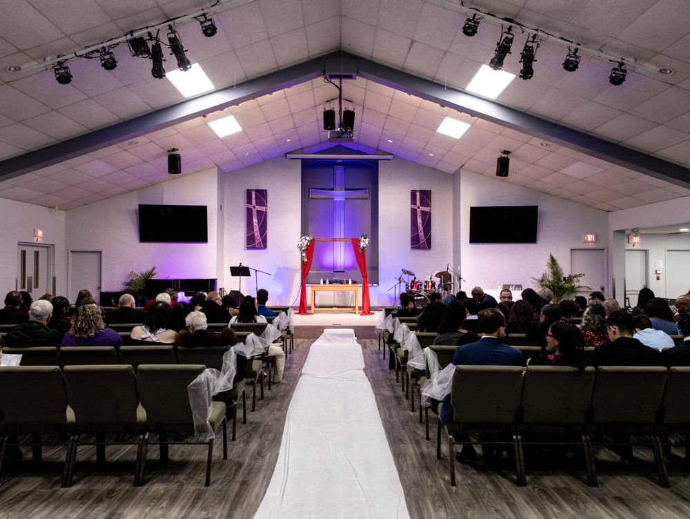 Modern church sanctuary with purple lighting, white aisle runner and rows of chairs.