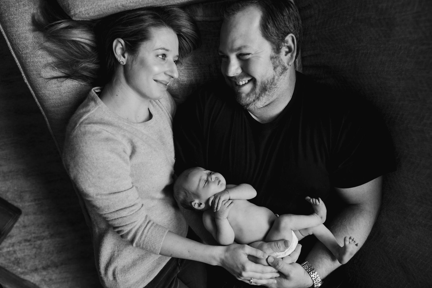 Black and white photo of tender family moments captured on a comfortable couch.