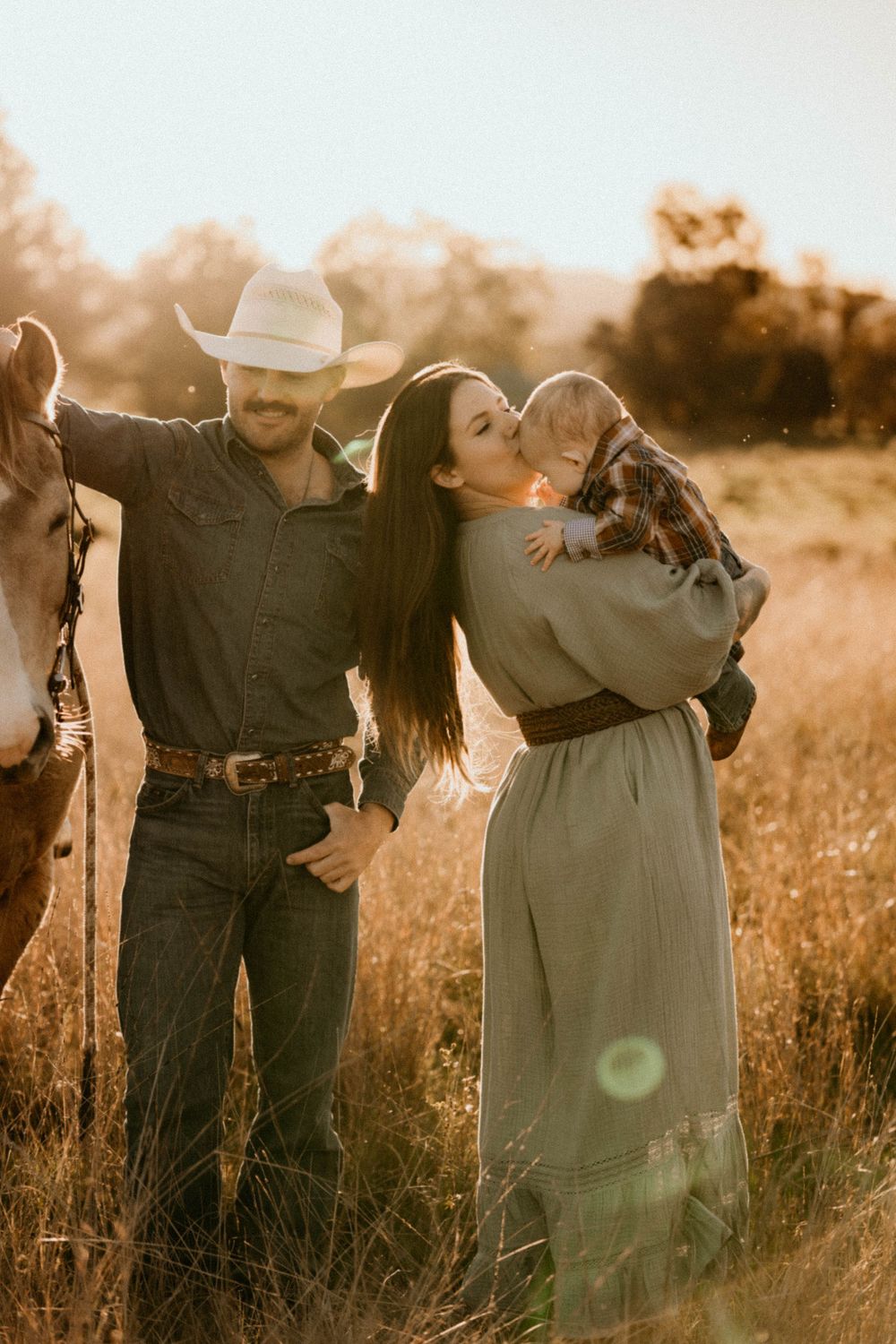 A family enjoying a tender moment together in a sun-drenched field during golden hour.