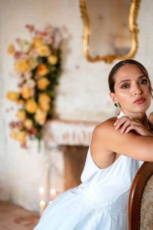 Elegant white bridal gown photographed in rustic setting with floral decorations.