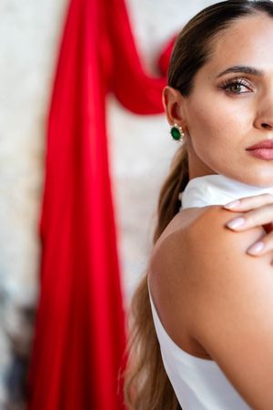 Close up portrait with red fabric backdrop showing partial face and dramatic lighting.