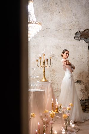 Moody bridal scene with crystal chandelier and gold candelabra in vintage setting.