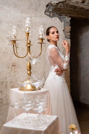 Artistic bridal portrait with vintage gold candelabra and textured stone wall backdrop.