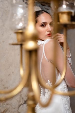 Creative bridal portrait framed through gold candelabra arms in vintage setting.