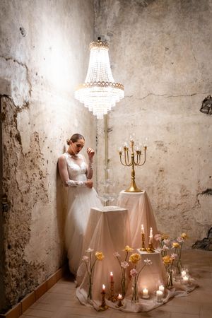 Elegant white chandelier and candelabra create romantic ambiance against distressed stone walls.