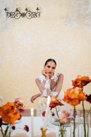 Elegant table setting with vibrant orange flowers and white decor against distressed wall.