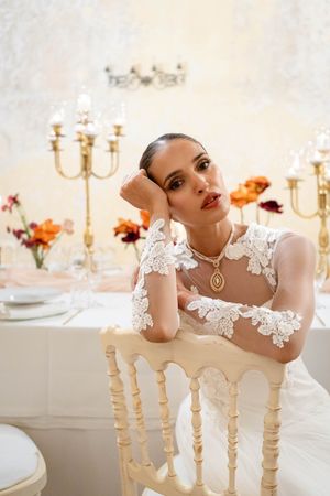White lace dress details shown against elegant table setting with orange floral arrangements.
