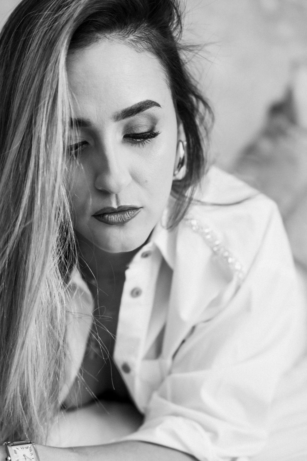 Black and white portrait with dramatic lighting showcasing long hair and smokey eye makeup.
