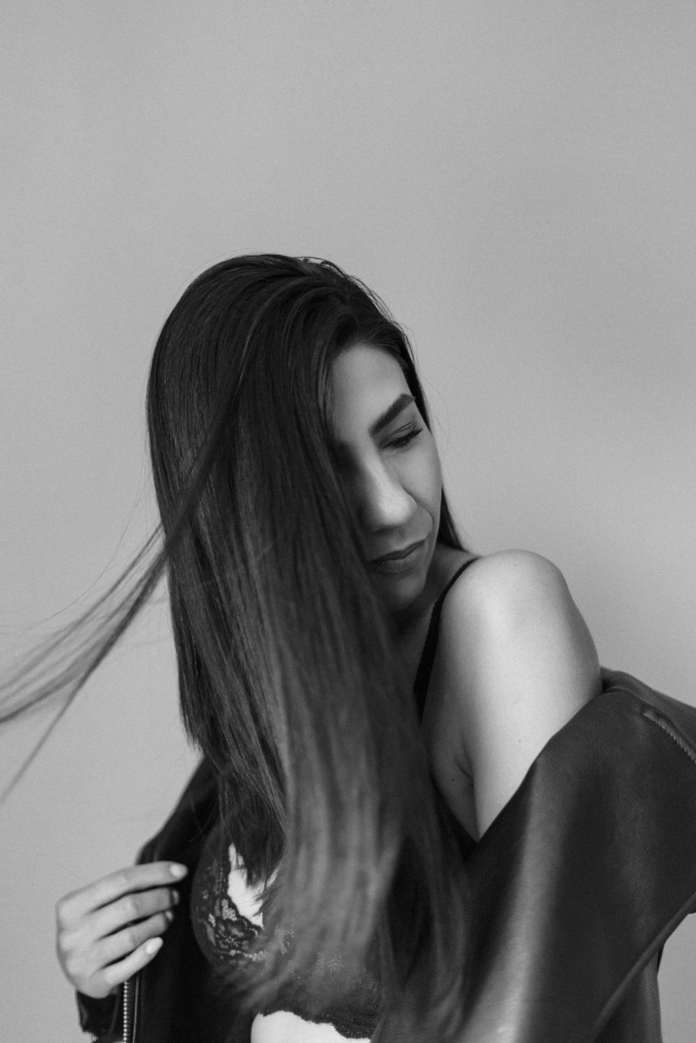 Dramatic black and white portrait with flowing dark hair against light background.