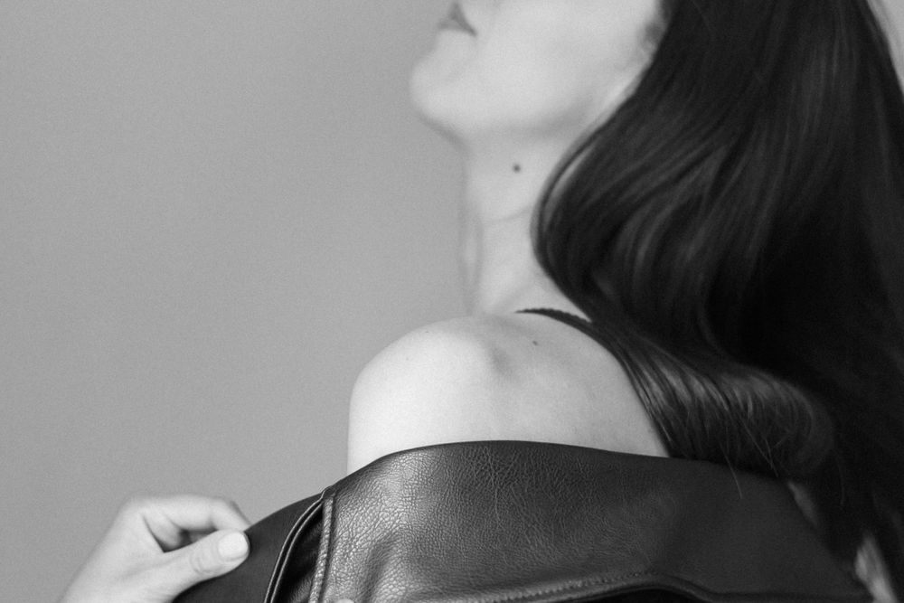 Artistic black and white close-up showing shoulder and leather jacket.