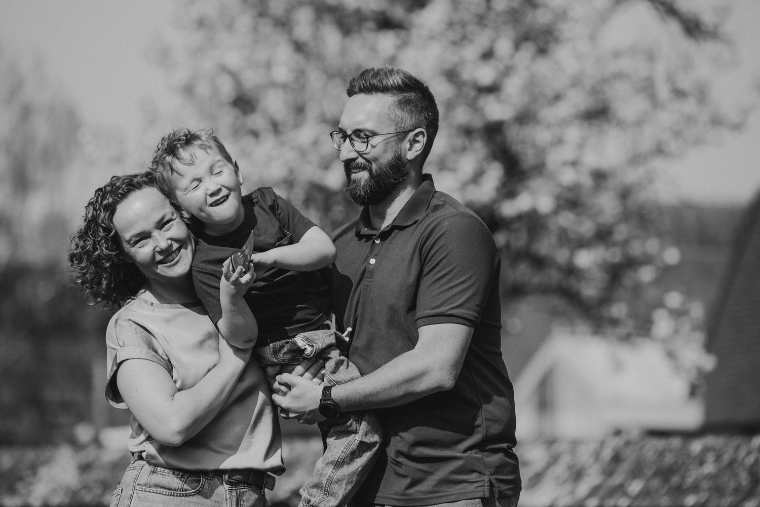 Een familie van mama, papa en zoontje. Ze hebben plezier. Papa draagt zijn zoontje en mama knuffelt hem.