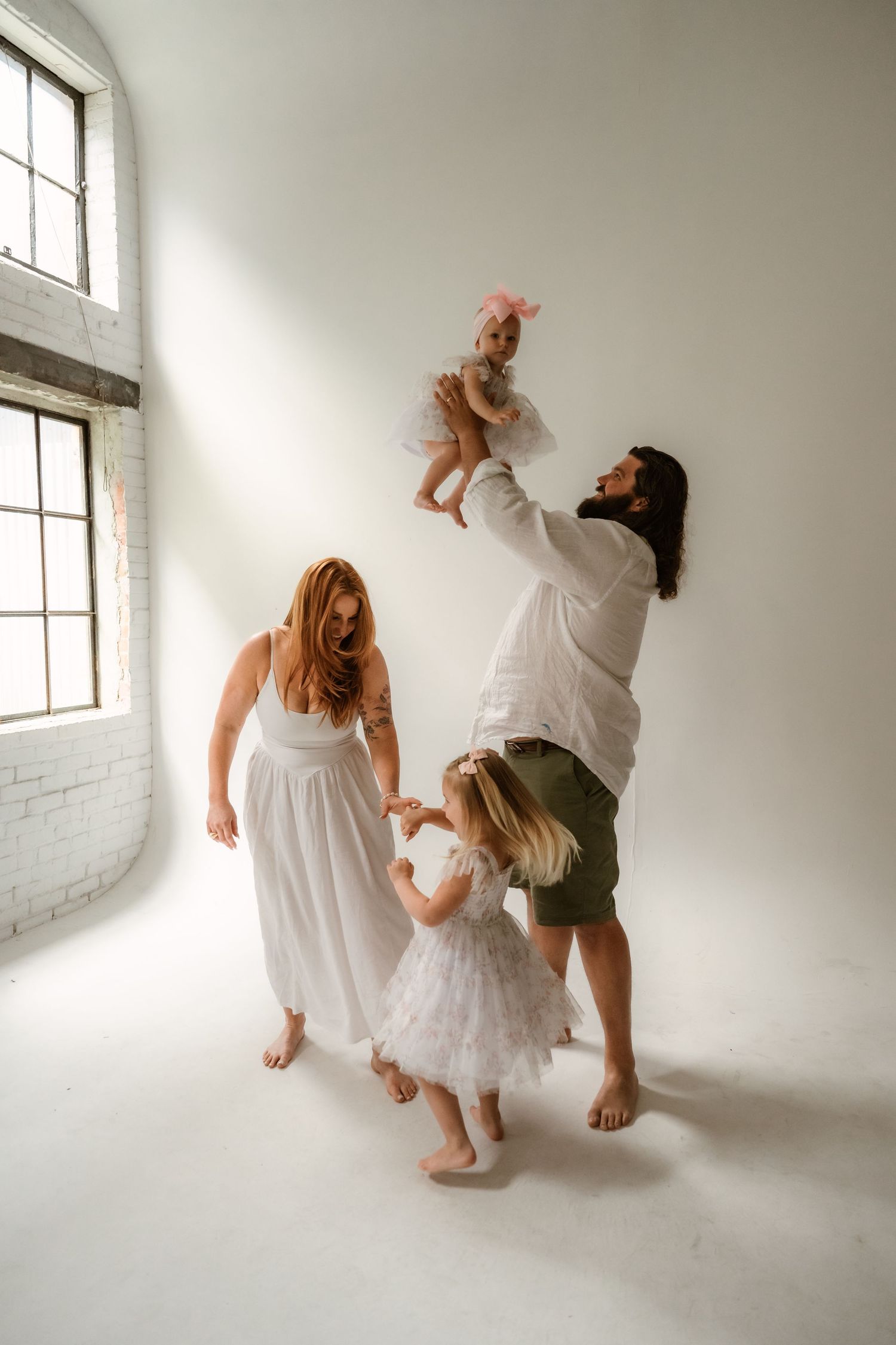 Artistic dance performance sequence in white clothing against minimalist white studio backdrop.
