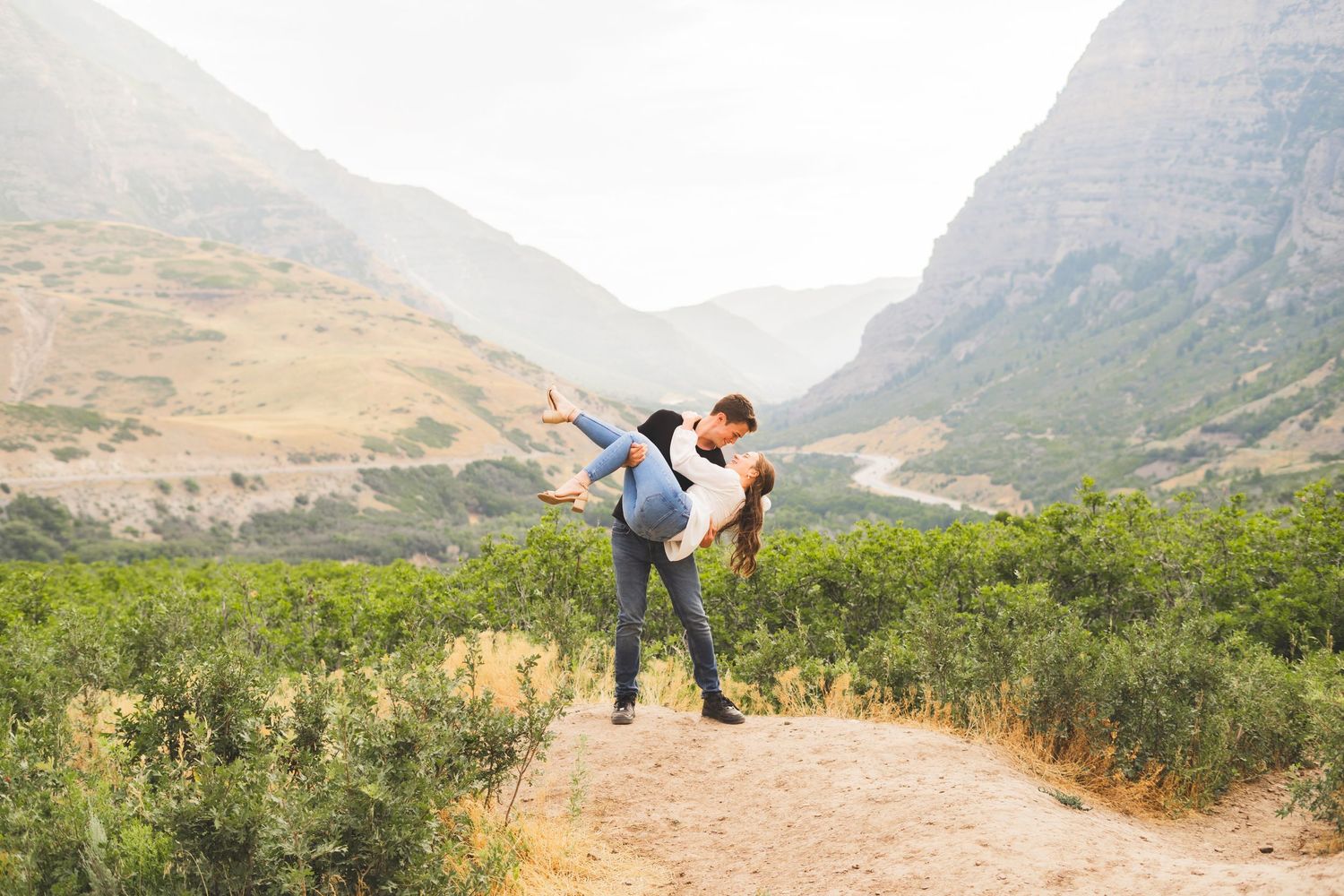 Romantic couple poses against stunning mountain landscape backdrop.