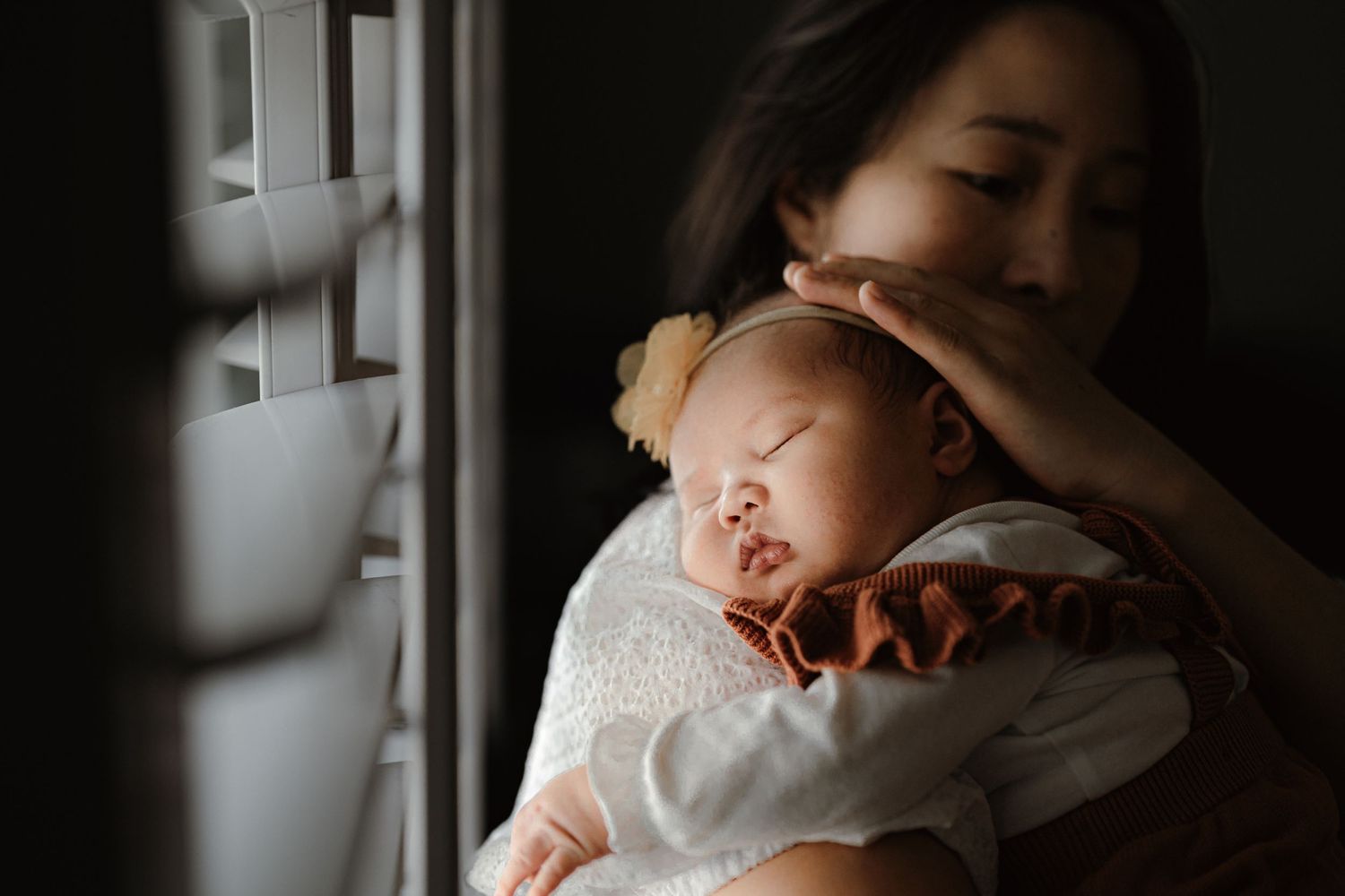 A tender moment between parent and infant by a sunlit window.