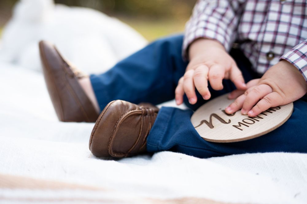 Close-up of small brown leather boots with writing on the soles.