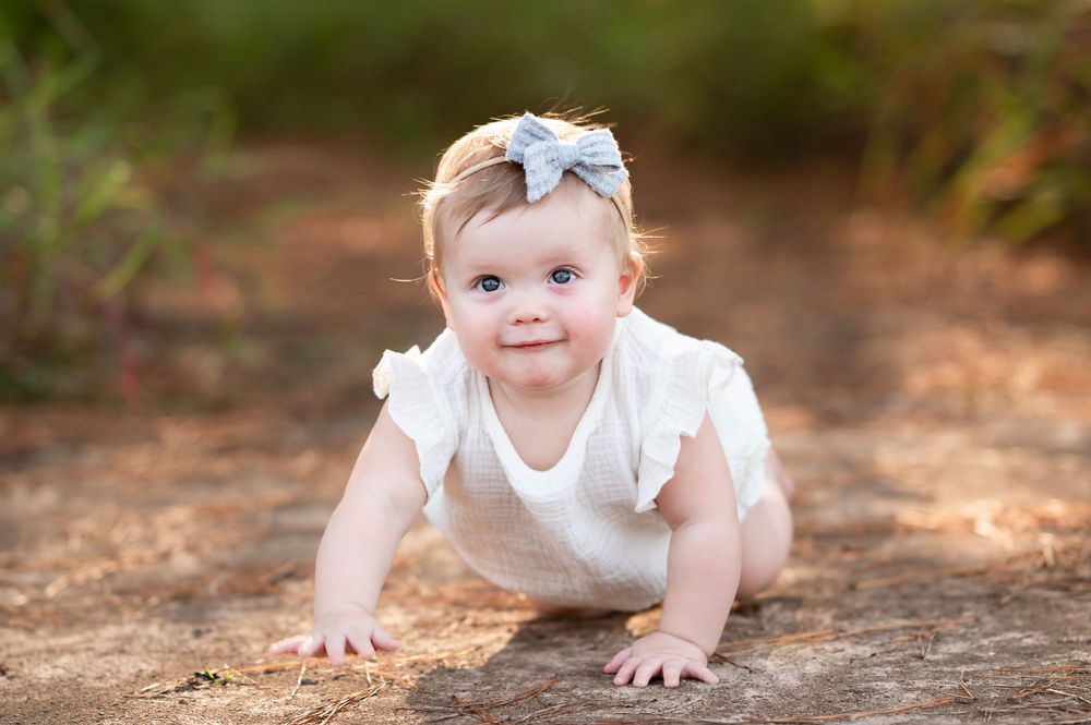 Crawling sequence on the ground wearing a white outfit with a bow accent.
