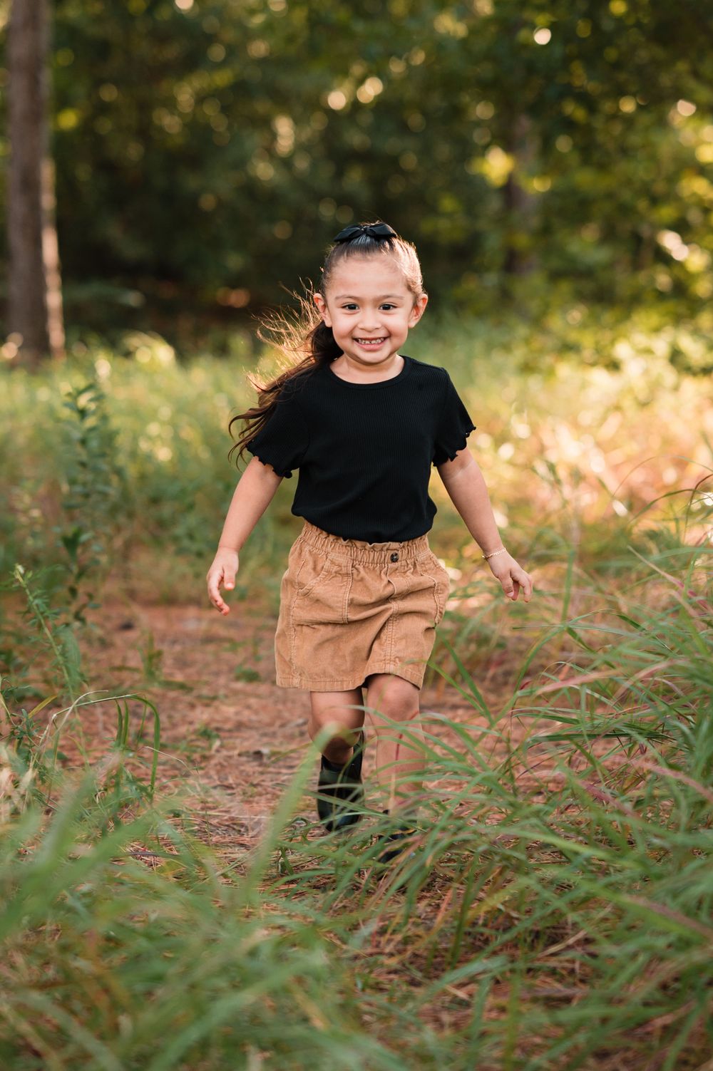 Dynamic action shots running through tall grass wearing a black top and tan shorts.